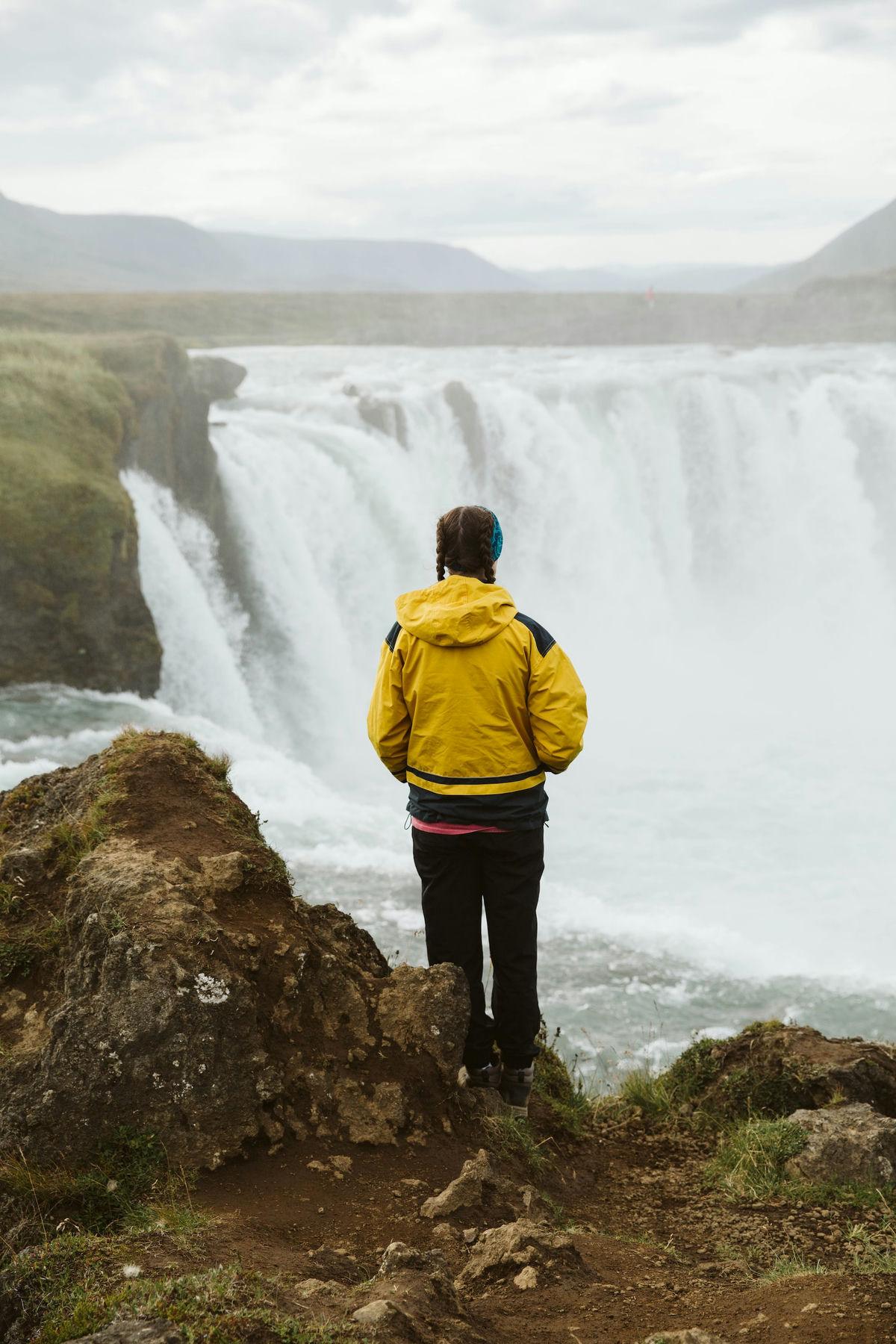 Woman stands in front of waterfall Woman stands in front of waterfall