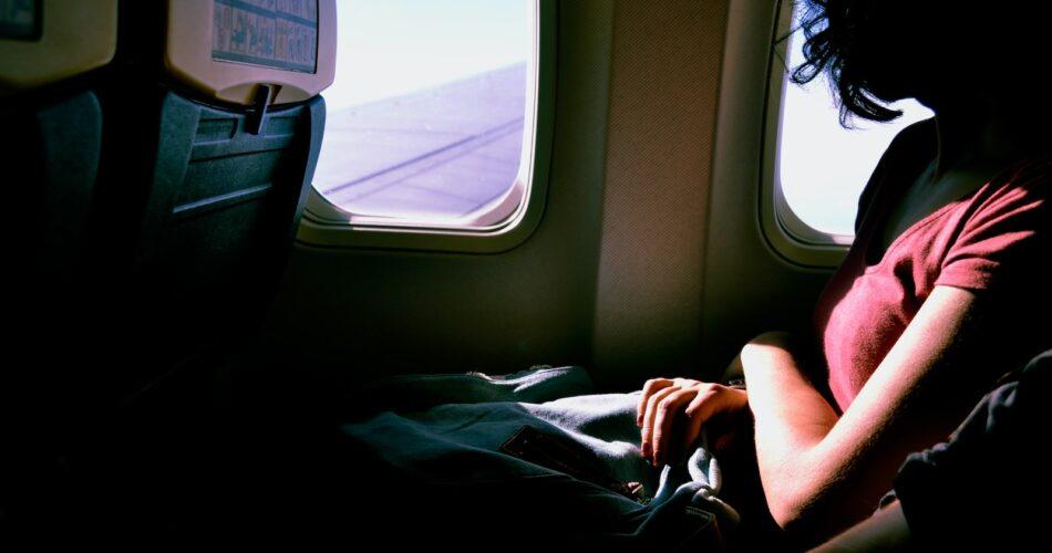 woman riding in airplane while watching at window