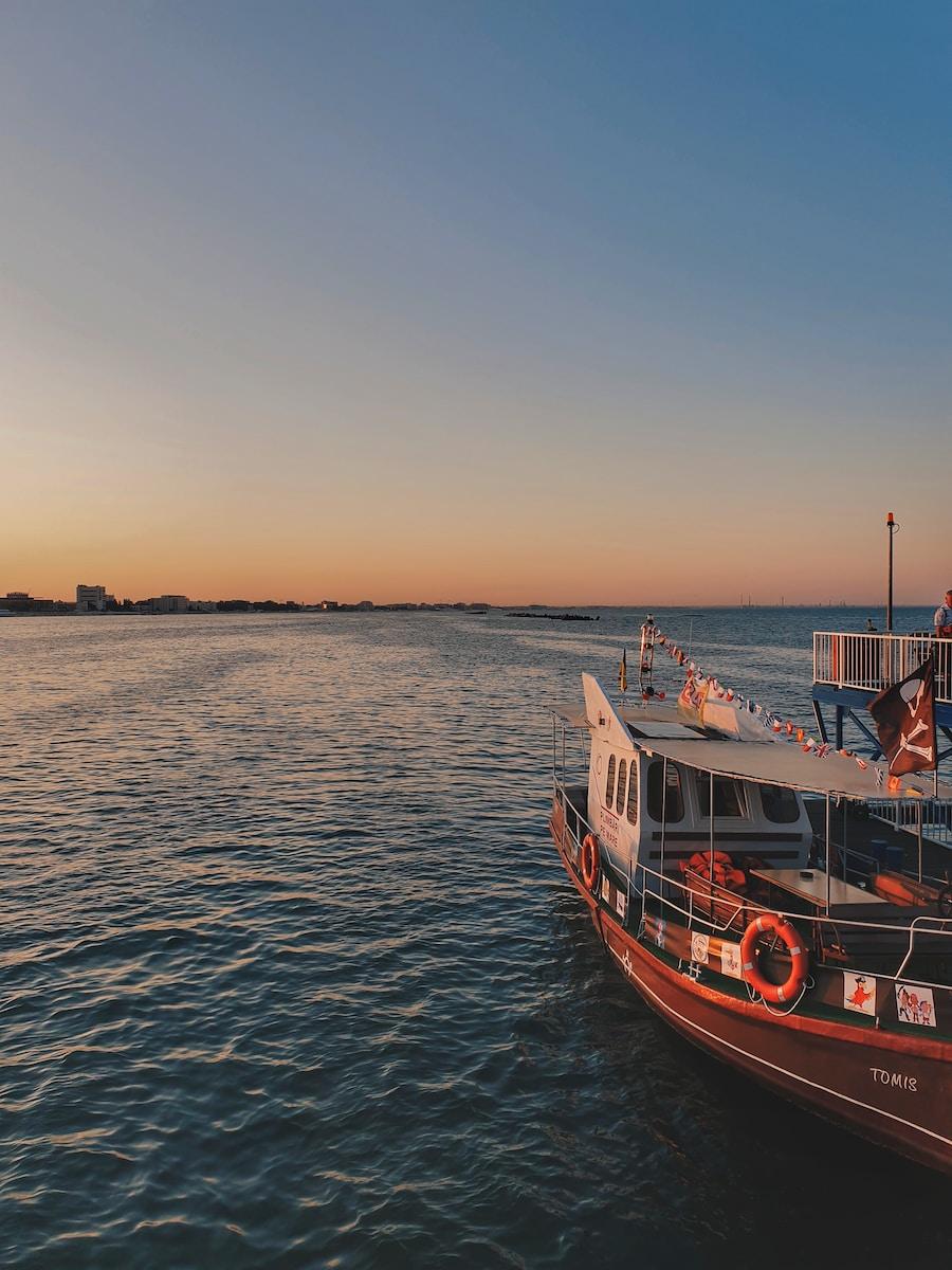 Photo by Odette Ion red and white boat on body of water at golden hour