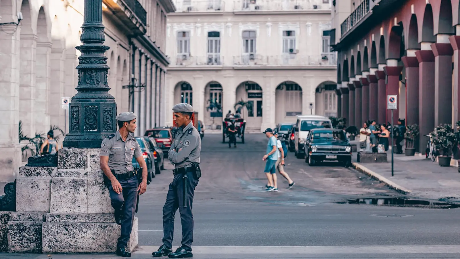 Photo by Yuting Gao Police officers conversing in a scenic Havana street, showcasing historic architecture.