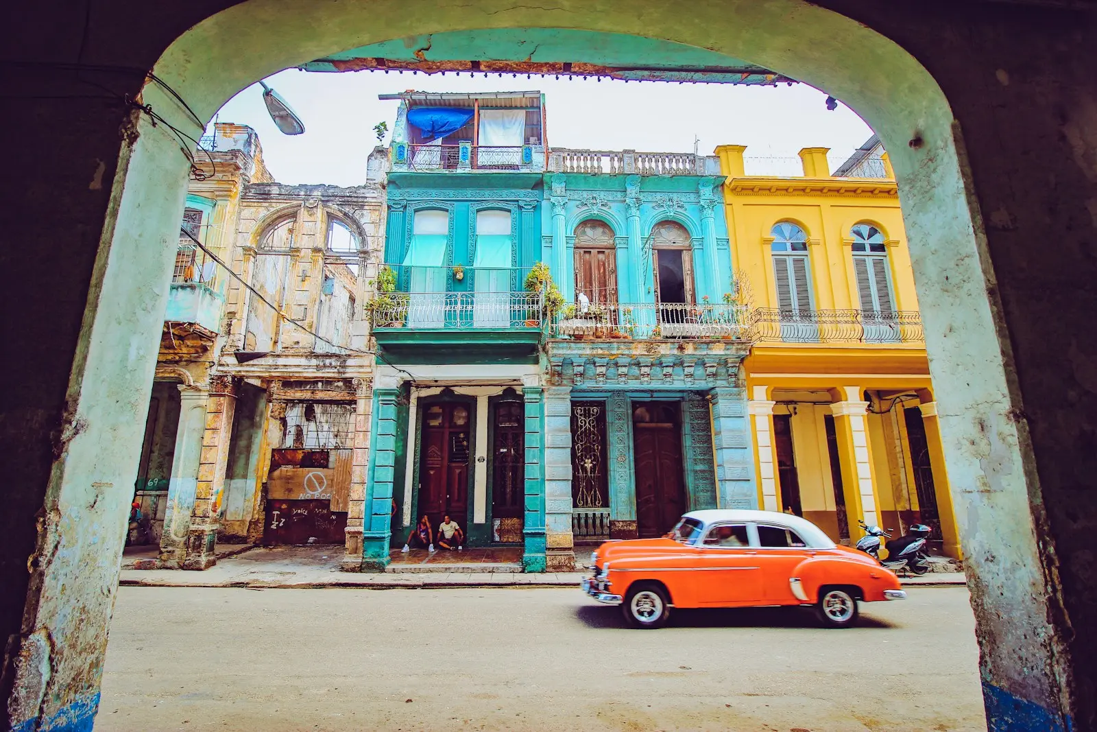 Photo by Florian Wehde orange and white sedan parked beside brown concrete building during daytime