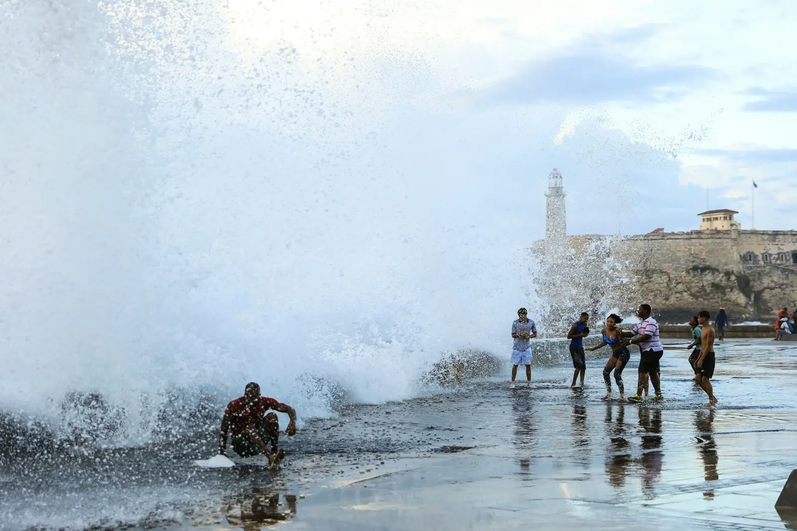 Photo by Dylan Shaw a group of people standing on top of a beach next to a wave