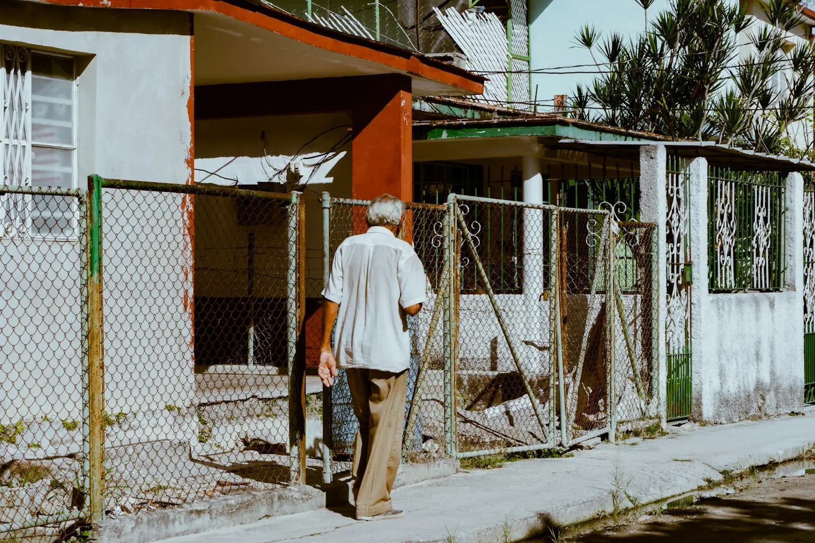 Photo by Kevin Torres a man walking down a street next to a fence